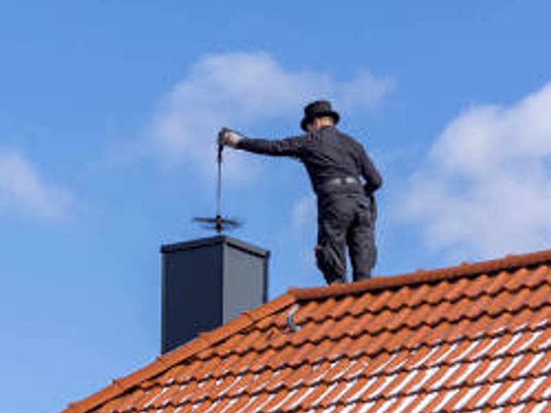 chimney sweep at work on the flue from the roof on a chimney in Woodbridge, NJ